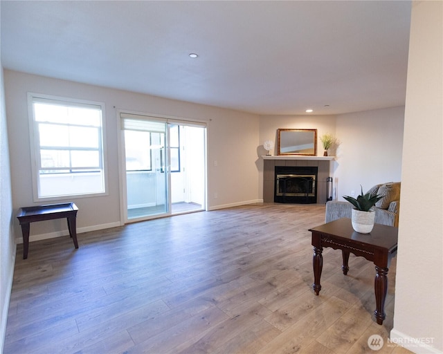 living area with light wood-type flooring, a fireplace, baseboards, and recessed lighting