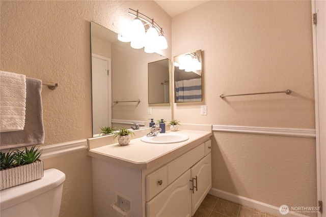 bathroom featuring a textured wall, vanity, tile patterned flooring, and toilet