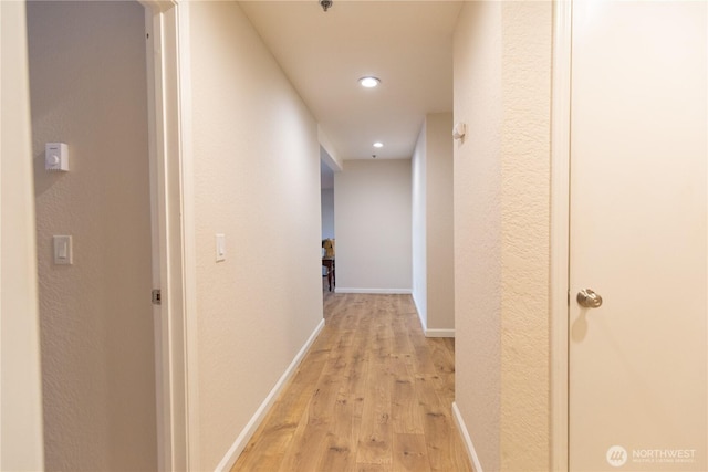 hallway featuring light wood-style floors, recessed lighting, and baseboards