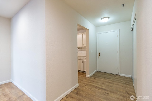 hallway with light wood-style floors and baseboards