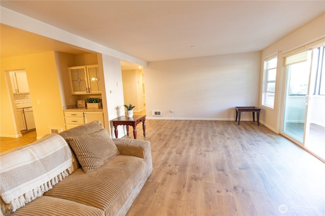 living room with light wood-type flooring, baseboards, and visible vents