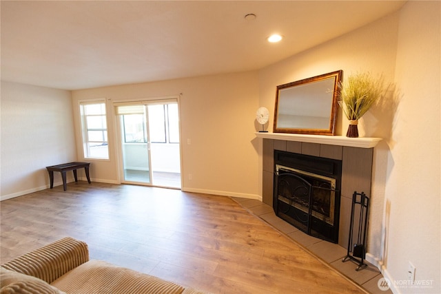 living area featuring baseboards, a tiled fireplace, wood finished floors, and recessed lighting