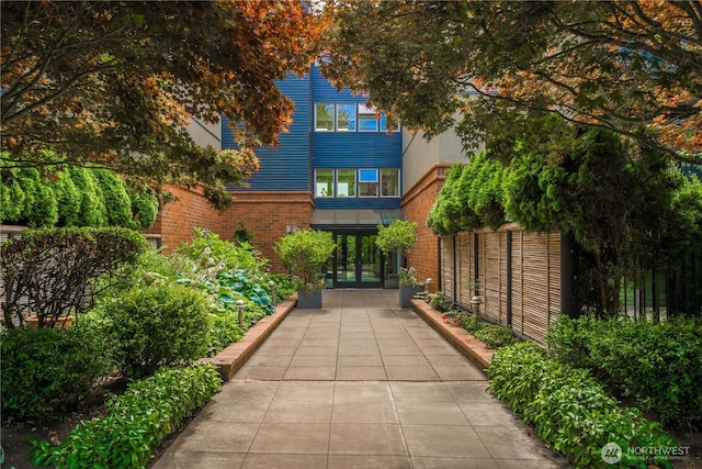 view of front of house featuring french doors, brick siding, and fence