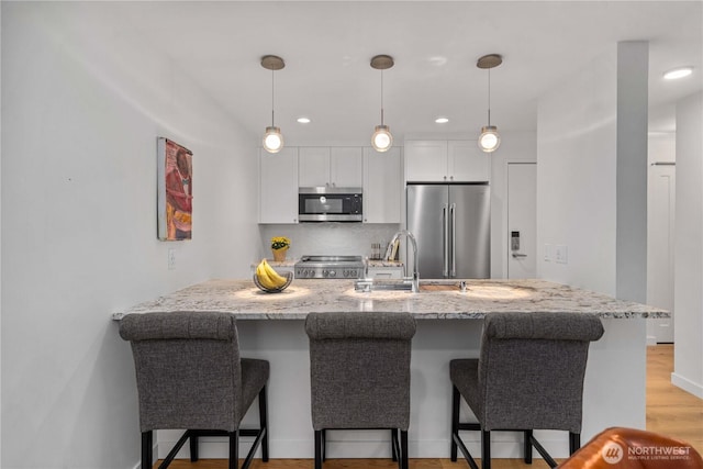 kitchen featuring stainless steel appliances, light stone counters, and a breakfast bar area