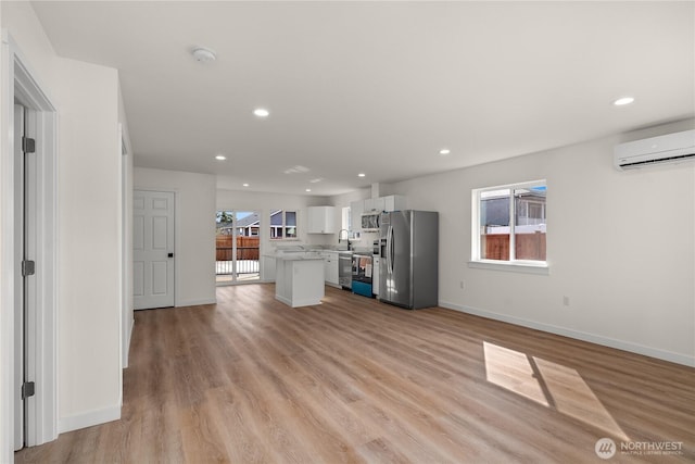 unfurnished living room featuring light wood-type flooring, a sink, recessed lighting, and a wall mounted AC