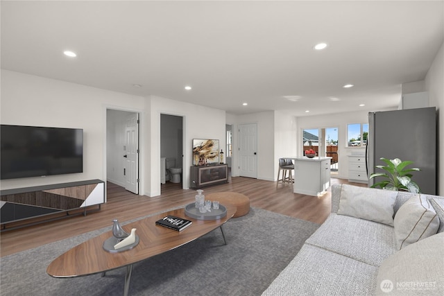 living area featuring baseboards, wood finished floors, and recessed lighting