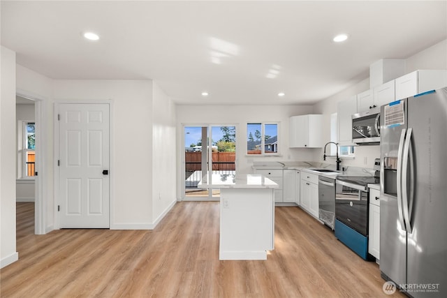 kitchen featuring stainless steel appliances, white cabinets, light countertops, and light wood-style floors