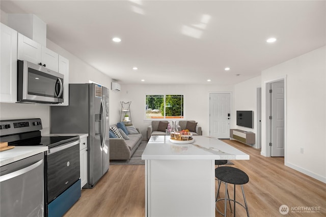 kitchen featuring a kitchen island, a breakfast bar, open floor plan, stainless steel appliances, and light countertops