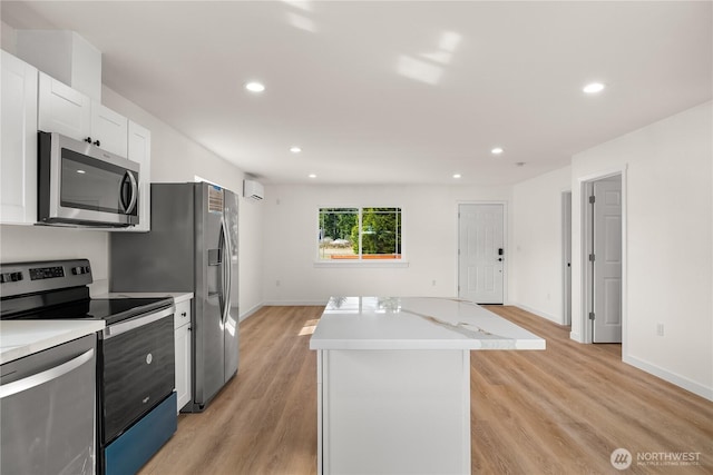 kitchen featuring stainless steel appliances, a center island, light countertops, and light wood-style flooring