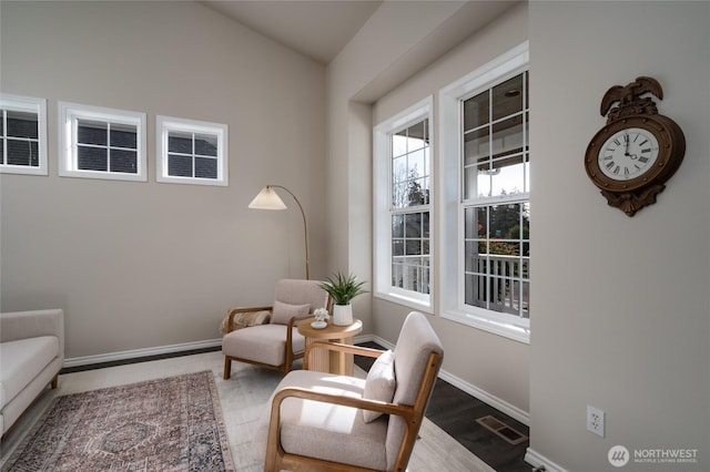 living area with wood finished floors, visible vents, and baseboards