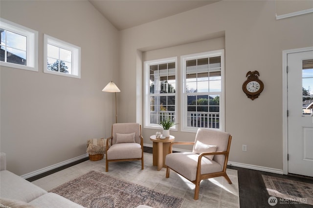 living area featuring baseboards, vaulted ceiling, and a wealth of natural light