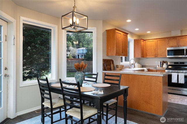 kitchen featuring stainless steel appliances, recessed lighting, light countertops, a sink, and a peninsula