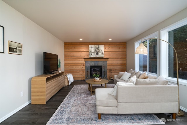 living area featuring wooden walls, baseboards, a tile fireplace, dark wood-style flooring, and recessed lighting