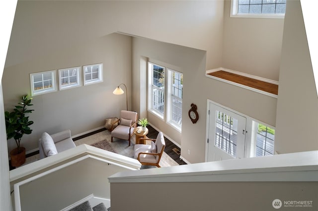 living area with a high ceiling, plenty of natural light, and baseboards