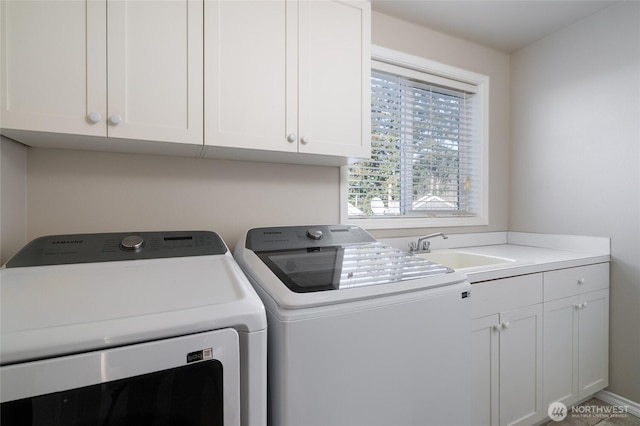 laundry area featuring washing machine and clothes dryer, a sink, and cabinet space