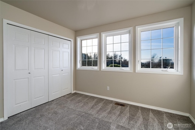 unfurnished bedroom featuring a closet, carpet flooring, visible vents, and baseboards