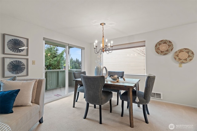 dining space with visible vents, a notable chandelier, and light colored carpet