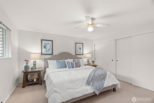 bedroom with light carpet, two closets, and a ceiling fan