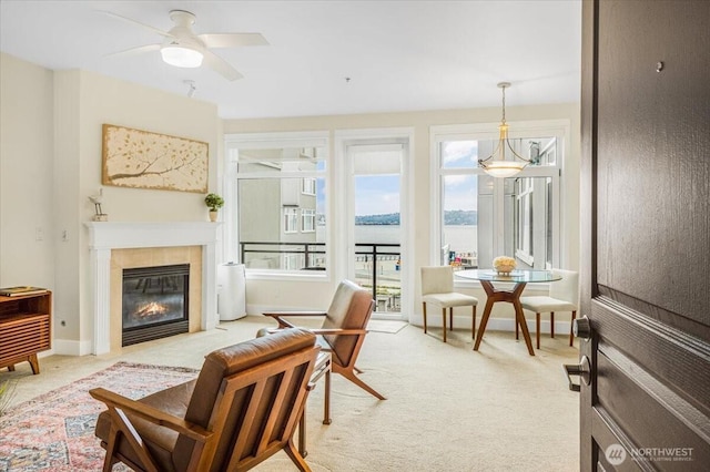 living area with carpet floors, a water view, baseboards, and a tiled fireplace