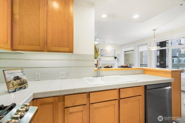 kitchen with tile counters, dishwasher, a peninsula, a sink, and recessed lighting