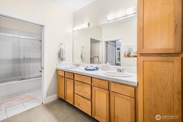 full bath with bath / shower combo with glass door, tile patterned flooring, a sink, and double vanity