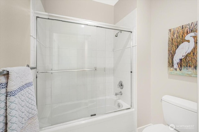 full bath with toilet and shower / bath combination with glass door