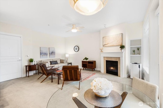 living room featuring ceiling fan, a tiled fireplace, and light colored carpet