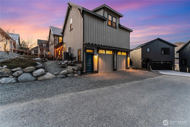 modern farmhouse style home featuring metal roof, gravel driveway, a standing seam roof, central air condition unit, and board and batten siding