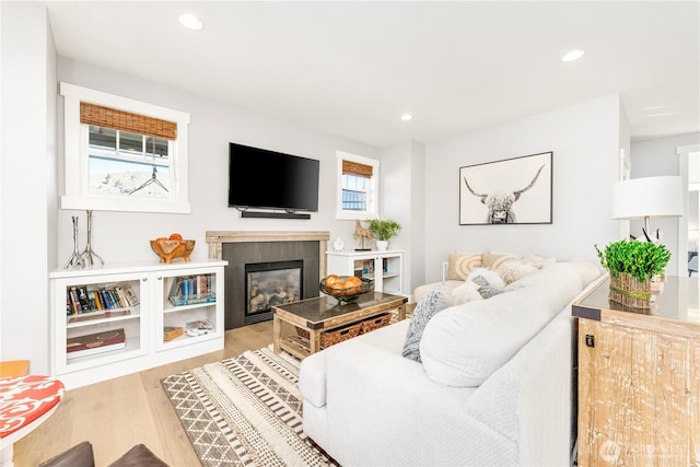 living room featuring a tiled fireplace, wood finished floors, and recessed lighting