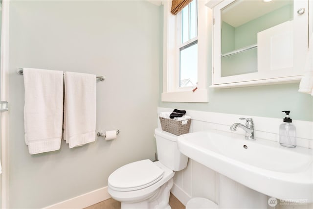 bathroom with walk in shower, a sink, toilet, and baseboards