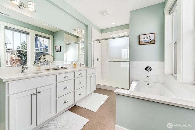 full bath featuring double vanity, a stall shower, a sink, and a bath