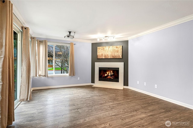 unfurnished living room featuring baseboards, wood finished floors, a fireplace with flush hearth, and crown molding