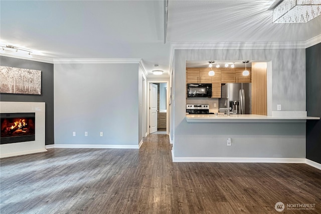 unfurnished living room with dark wood-style floors, ornamental molding, a lit fireplace, and baseboards