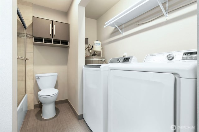 laundry area featuring laundry area, baseboards, light wood finished floors, and washing machine and clothes dryer