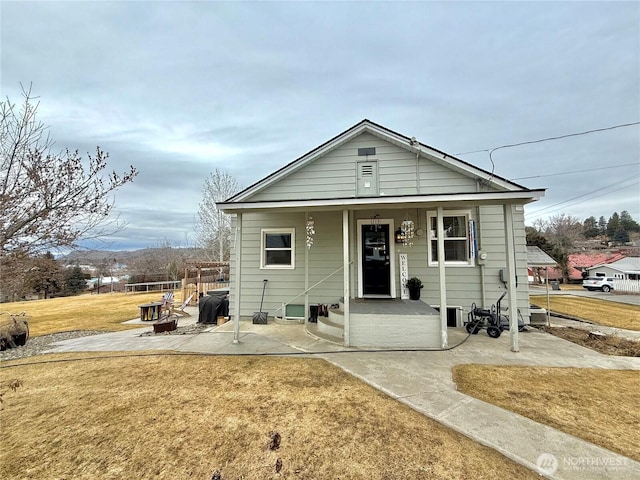 bungalow-style house featuring covered porch, a patio, and a front yard