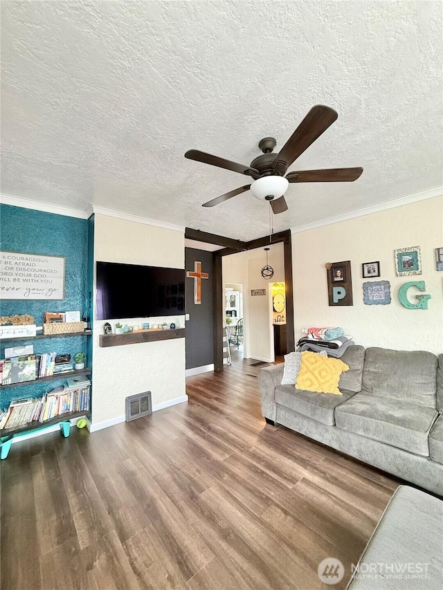 living area with a textured ceiling, wood finished floors, visible vents, a ceiling fan, and ornamental molding