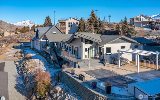 back of property featuring a deck with mountain view, stairs, a patio, and fence