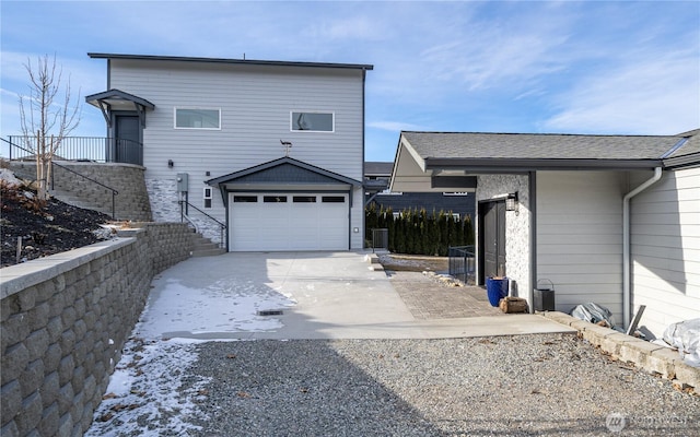 view of front facade with concrete driveway and roof with shingles