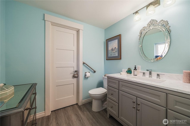 bathroom featuring toilet, vanity, baseboards, and wood finished floors