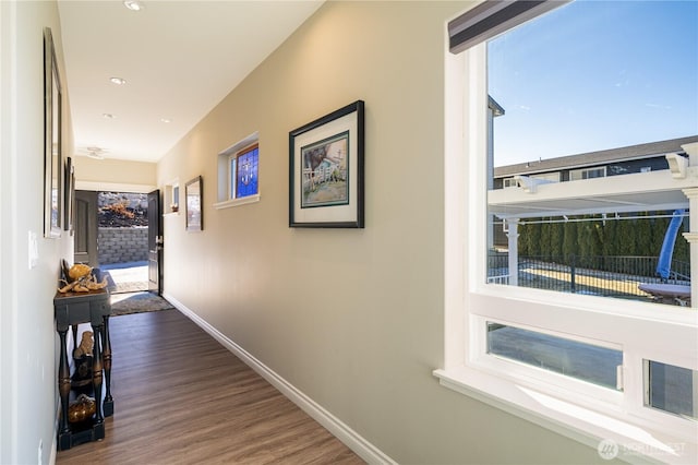 corridor with plenty of natural light, baseboards, and wood finished floors