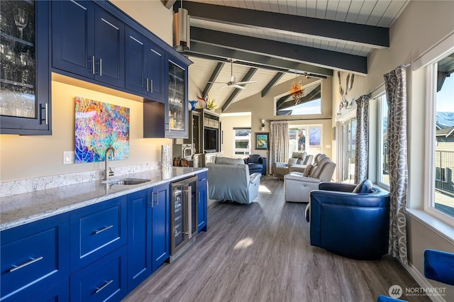 kitchen with blue cabinets, wine cooler, lofted ceiling with beams, and a sink