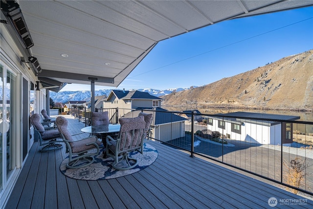 wooden terrace with outdoor dining space and a mountain view