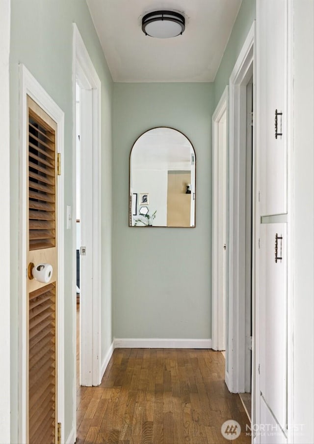 hallway with dark wood-style flooring and baseboards