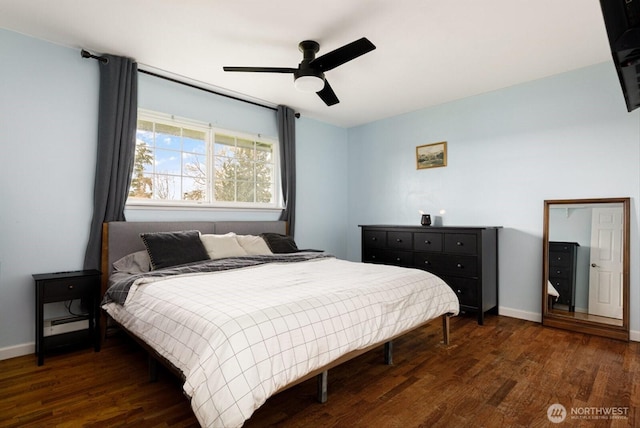 bedroom featuring a baseboard heating unit, dark wood-style flooring, a ceiling fan, and baseboards