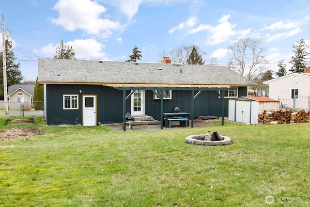 back of house featuring a lawn, a fire pit, an outdoor structure, and a shed