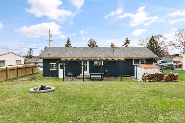 back of property with a storage unit, a yard, an outdoor fire pit, and fence