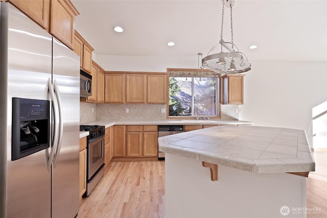 kitchen with tasteful backsplash, light wood finished floors, a kitchen bar, recessed lighting, and stainless steel appliances