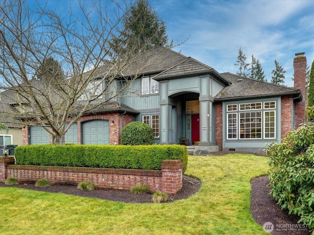 traditional-style home featuring brick siding, a chimney, an attached garage, crawl space, and a front lawn