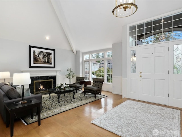 foyer featuring high vaulted ceiling, a notable chandelier, wood finished floors, a high end fireplace, and beam ceiling