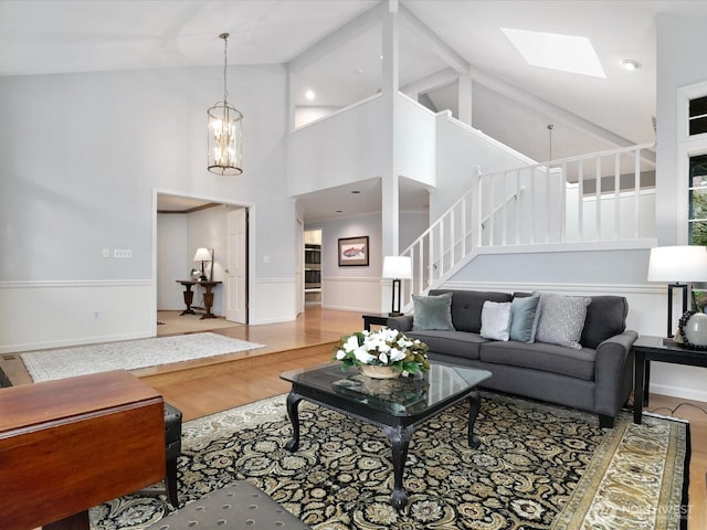 living room featuring a skylight, stairway, wood finished floors, and wainscoting